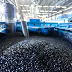 Granuli neri, **materie prime seconde**, pronti per essere trasformati in nuovi prodotti in un impianto industriale.