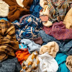 Un mucchio di vestiti colorati, pronti per la raccolta indumenti usati. Maglioni, sciarpe e tessuti di varie fantasie e trame.