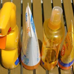 Prodotti solari scaduti, tra cui una crema solare spray e una lozione, pronti per essere smaltiti. Dove si buttano le creme scadute?