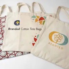 Diverse buste della spesa in cotone, alcune con stampe geometriche e altre con loghi colorati, pronte per lo shopping sostenibile.