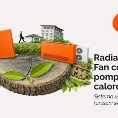 Un fancoil a pavimento arancione, un radiatore e pannelli solari su un tronco d'albero, con case e un edificio sullo sfondo.