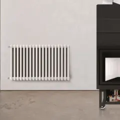 Termocamino moderno con dettagli idraulici visibili sotto, accanto a un radiatore bianco. Illustra come funziona un termocamino per riscaldare l'ambiente.