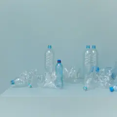 Bottiglie di plastica vuote, alcune schiacciate, su un piano. Un promemoria visivo della necessità di alternative alla plastica.
