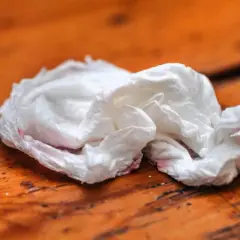 Tovaglioli sporchi, con tracce rosse, abbandonati su un tavolo di legno. Dove si buttano?