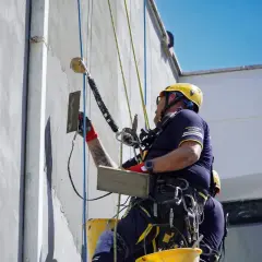 Lavoratori in corda stanno rifinendo una facciata, forse per un progetto di riqualificazione con bonus facciate 2026.