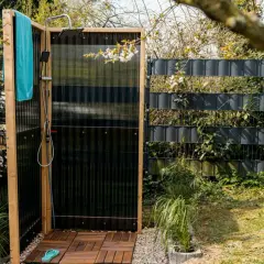 Doccia da giardino fai da te con pedana in legno, telo azzurro e rubinetto. Perfetta per rinfrescarsi all'aperto.
