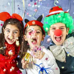 Bambini festosi con vestiti di carnevale creativi, realizzati con materiale riciclato, lanciano coriandoli.