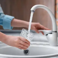 Mani che riempiono un bicchiere d'acqua dal rubinetto. L'acqua sanitaria cos'è? È l'acqua potabile che arriva nelle nostre case.