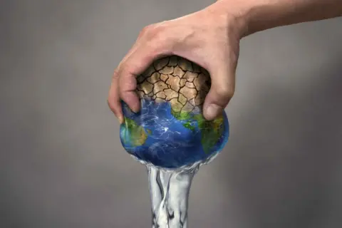 Mano che stringe la Terra, con terra arida che si sgretola e acqua che cola. Simboleggia il significato di overshoot day: il giorno in cui consumiamo più risorse di quelle che il pianeta può rigenerare.