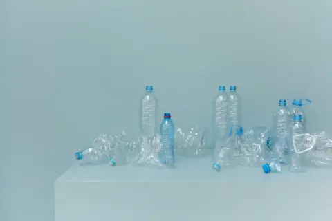 Bottiglie di plastica vuote, alcune schiacciate, su un piano. Un promemoria visivo della necessità di alternative alla plastica.