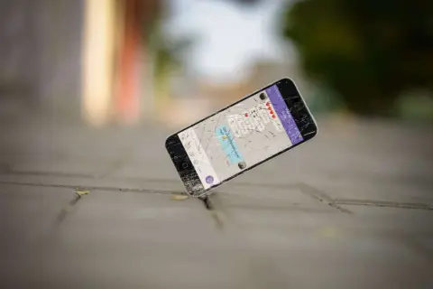 Un cellulare rotto giace a terra, forse è ora di capire dove si buttano i cellulari vecchi per un corretto smaltimento.