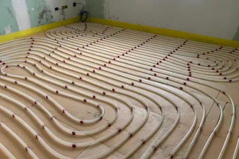 Installazione di tubi per riscaldamento a pavimento su pannelli isolanti. Un sistema efficiente per un comfort domestico.