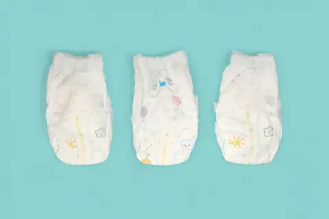 Tre pannolini per bambini con disegni colorati, pronti per essere smaltiti. Ecco dove si buttano i pannolini dei bambini.