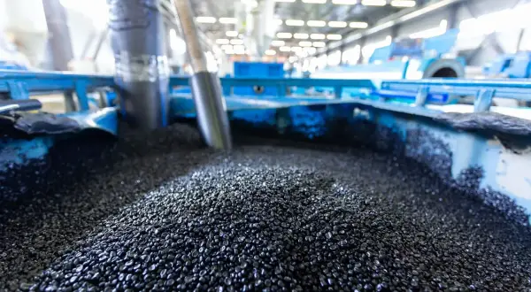 Granuli neri, **materie prime seconde**, pronti per essere trasformati in nuovi prodotti in un impianto industriale.