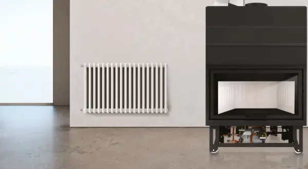 Termocamino moderno con dettagli idraulici visibili sotto, accanto a un radiatore bianco. Illustra come funziona un termocamino per riscaldare l'ambiente.