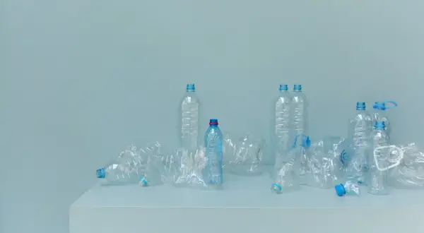 Bottiglie di plastica vuote, alcune schiacciate, su un piano. Un promemoria visivo della necessità di alternative alla plastica.