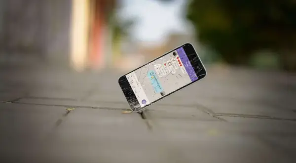 Un cellulare rotto giace a terra, forse è ora di capire dove si buttano i cellulari vecchi per un corretto smaltimento.