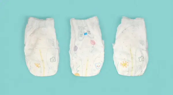 Tre pannolini per bambini con disegni colorati, pronti per essere smaltiti. Ecco dove si buttano i pannolini dei bambini.