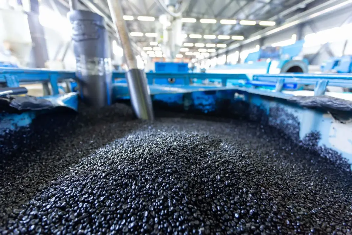 Granuli neri, **materie prime seconde**, pronti per essere trasformati in nuovi prodotti in un impianto industriale.