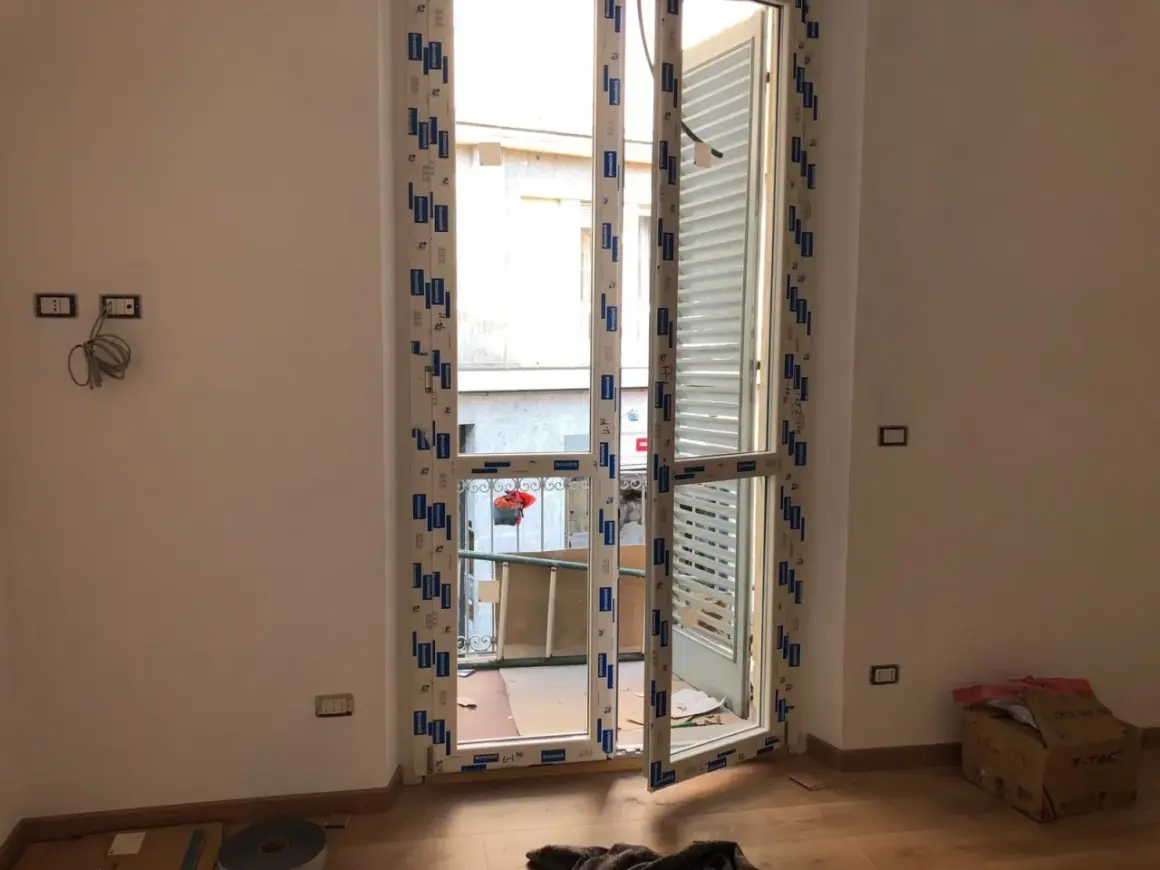 Nuova **doppia finestra per isolamento termico** installata in un ambiente in fase di ristrutturazione. Si intravede un cortile esterno.