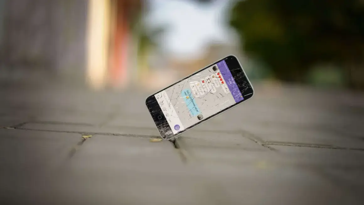 Un cellulare rotto giace a terra, forse è ora di capire dove si buttano i cellulari vecchi per un corretto smaltimento.