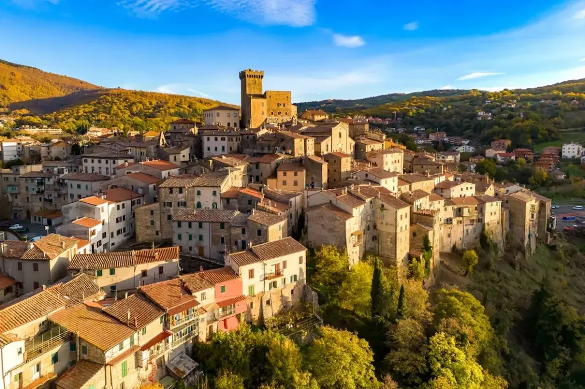 Borgo medievale su una collina, con un castello in cima. Un esempio di albergo diffuso significato, dove le case del paese offrono ospitalità.