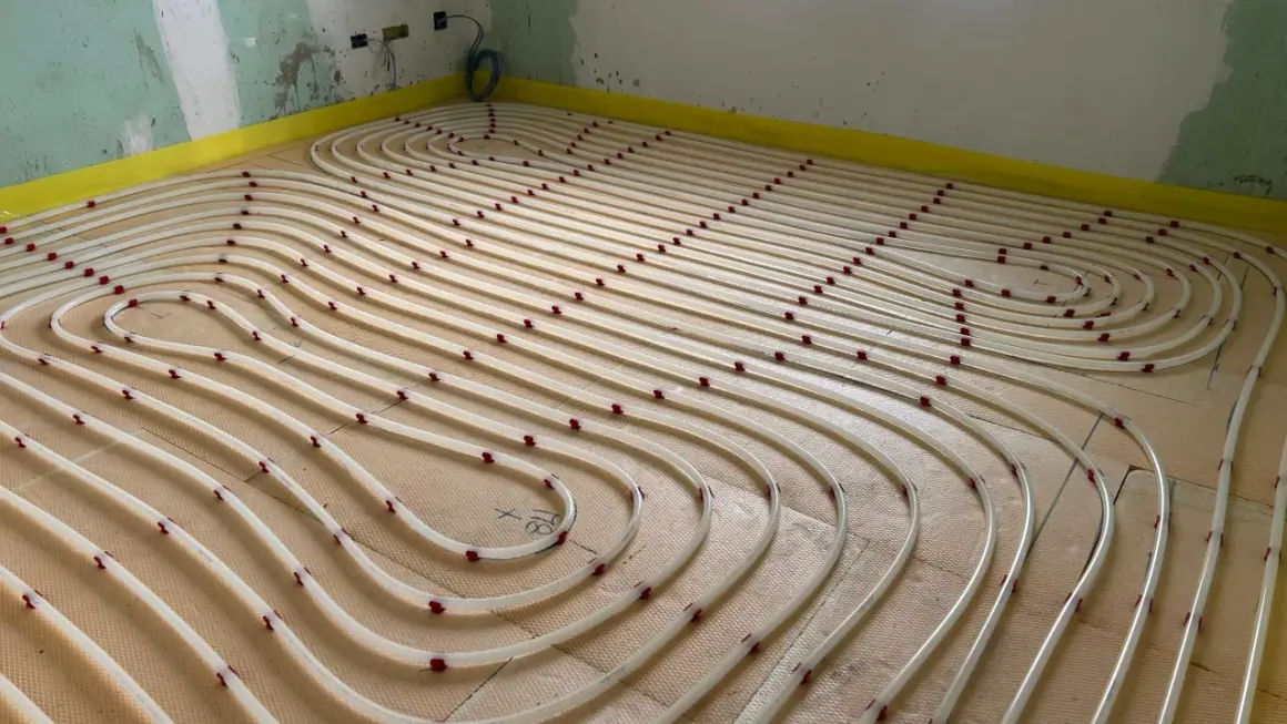 Installazione di tubi per riscaldamento a pavimento su pannelli isolanti. Un sistema efficiente per un comfort domestico.
