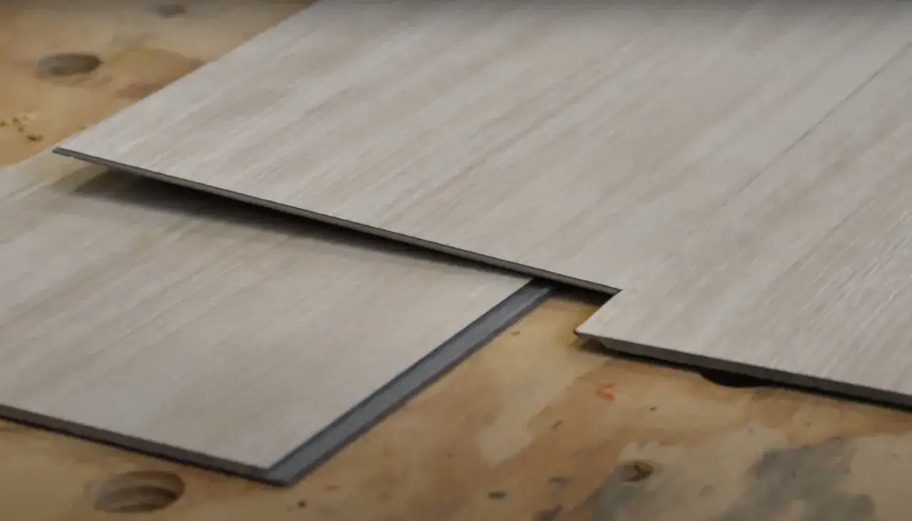 Posa pavimento pvc: tavole in laminato effetto legno chiaro, pronte per essere assemblate su una superficie grezza.