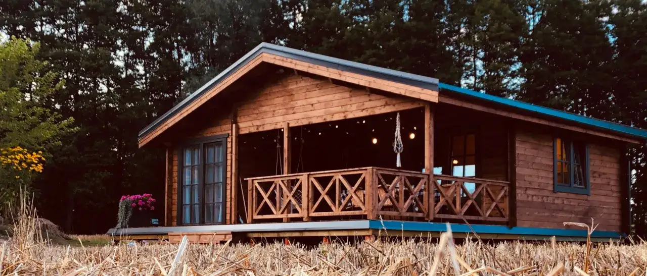 Casa in legno leggero e resistente, con veranda e luci decorative, immersa nel verde.