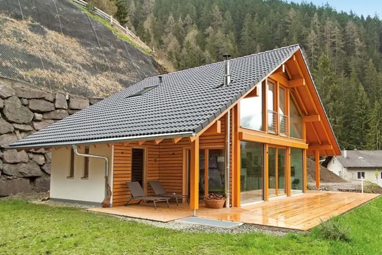 Casa moderna con ampi tetti in legno e vetrate, immersa nel verde di un bosco.