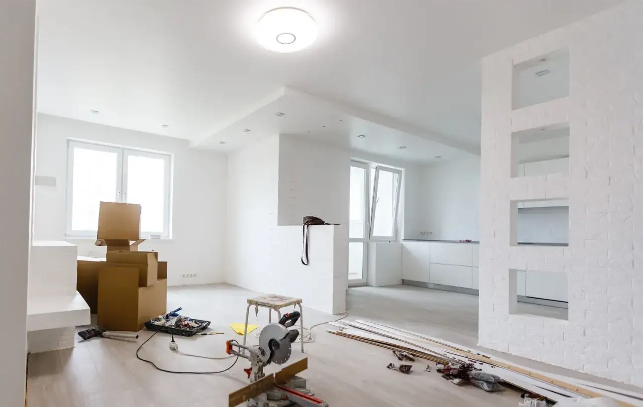 Interno in ristrutturazione con scatole, attrezzi e lastre di cartongesso pronte per essere installate.