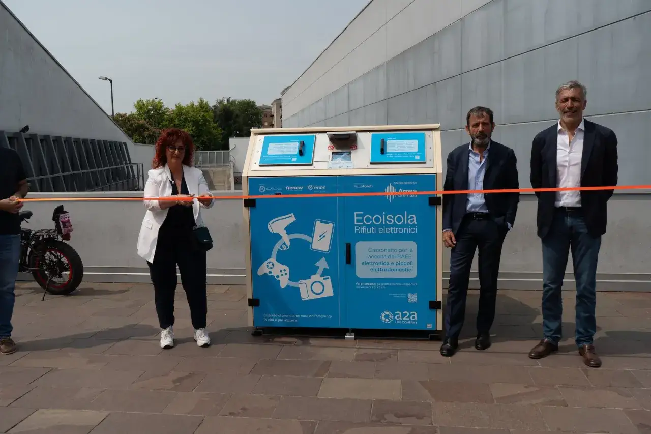 Inaugurazione Ecoisola, il nuovo punto dove si buttano le sigarette elettroniche e altri RAEE. Tre persone tagliano un nastro arancione.