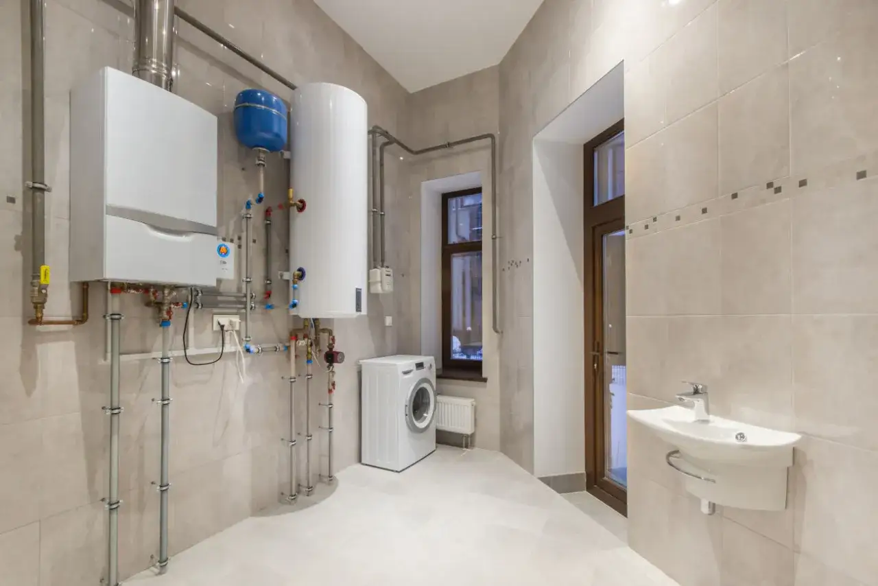 Caldaia e scaldabagno: ecco cos'è l'acqua sanitaria. Ambiente moderno con lavatrice e lavandino.