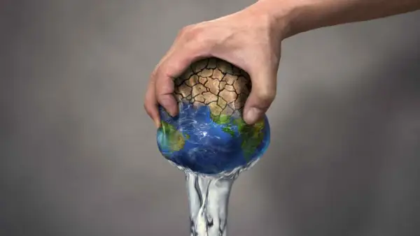 Mano che stringe la Terra, con terra arida che si sgretola e acqua che cola. Simboleggia il significato di overshoot day: il giorno in cui consumiamo più risorse di quelle che il pianeta può rigenerare.