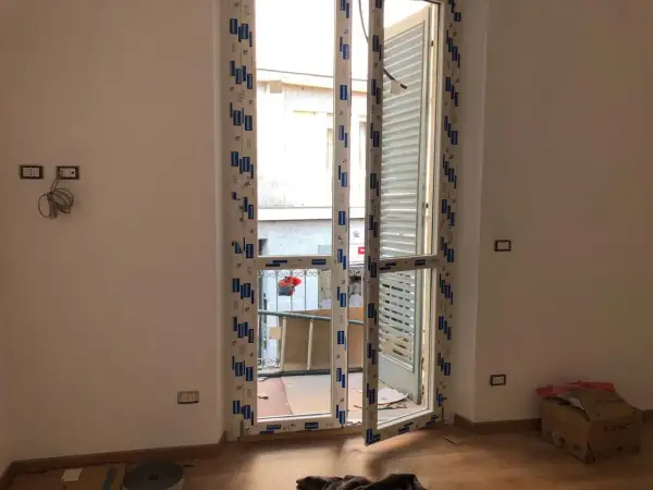 Nuova **doppia finestra per isolamento termico** installata in un ambiente in fase di ristrutturazione. Si intravede un cortile esterno.
