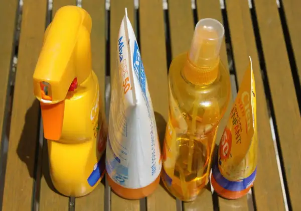 Prodotti solari scaduti, tra cui una crema solare spray e una lozione, pronti per essere smaltiti. Dove si buttano le creme scadute?