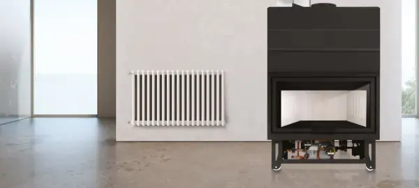 Termocamino moderno con dettagli idraulici visibili sotto, accanto a un radiatore bianco. Illustra come funziona un termocamino per riscaldare l'ambiente.
