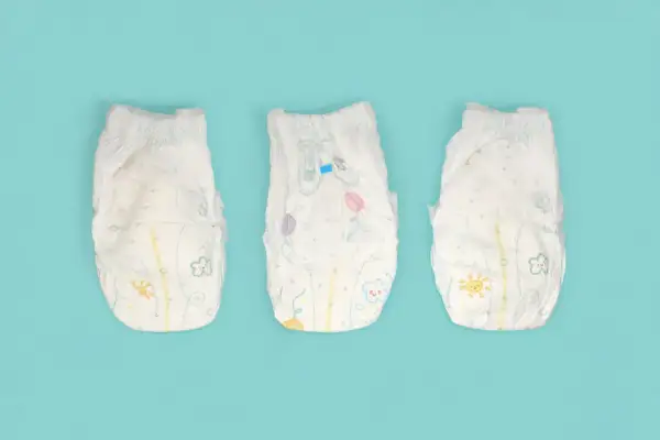 Tre pannolini per bambini con disegni colorati, pronti per essere smaltiti. Ecco dove si buttano i pannolini dei bambini.